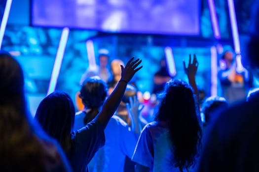 A lively worship scene with people raising their hands in an energetic concert setting.